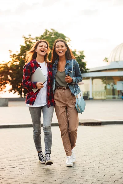 Duas Jovens Amigas Felizes Andando Juntas Rua Cidade Segurando Laptop — Fotografia de Stock