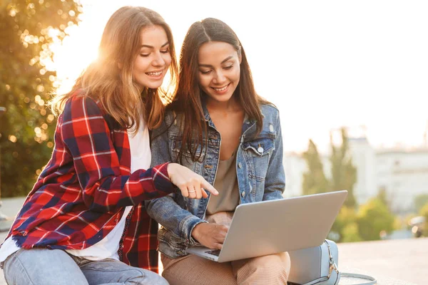 Duas Jovens Amigas Alegres Sentadas Juntas Rua Cidade Usando Laptop — Fotografia de Stock