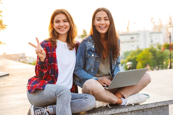 Zwei Fröhliche Junge Freundinnen Die Zusammen Der Stadtstraße Sitzen Laptop — Stockfoto