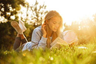 Bir kitap okuma oldukça genç bir kız parkta bir çim üzerinde döşeme sırt çantası ile portresi