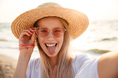 Bir selfie alarak neşeli genç kız yaz şapka ve plajda, vakit mayo