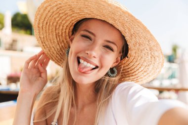 Bir selfie alarak neşeli genç kız yaz şapka ve güneşli kumsalda, dinlenme mayo