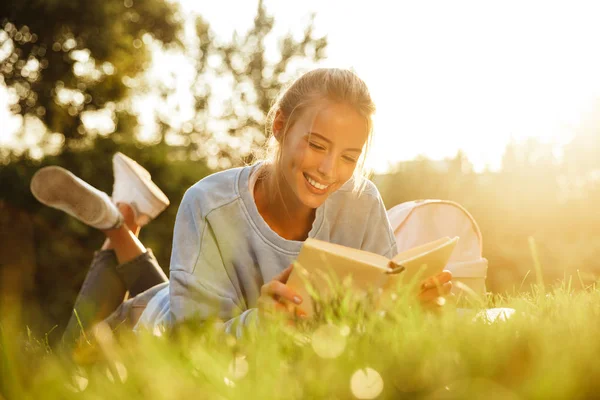 Portrait Smiling Young Girl Backpack Laying Grass Park Reading Book — Stock Photo, Image