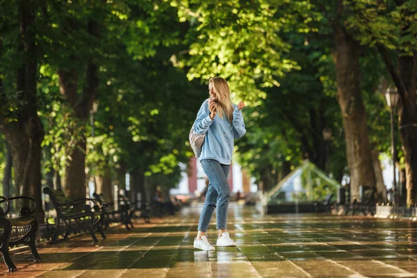 快乐的女孩与背包手持手机 在公园散步 — 图库照片