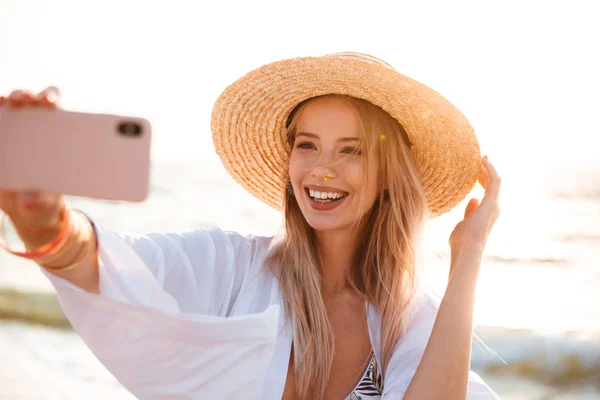 Outsretched の手で Selfie を取って夏帽子と水着 ビーチで時間を過ごす少女の笑みを浮かべてください — ストック写真