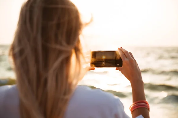 Вид Ззаду Молодої Дівчини Яка Фотографує Захід Сонця Пляжі Мобільним — стокове фото