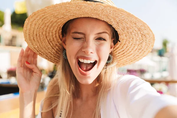 Bir selfie alarak genç kız yaz şapka ve güneşli kumsalda, dinlenme mayo heyecanlı