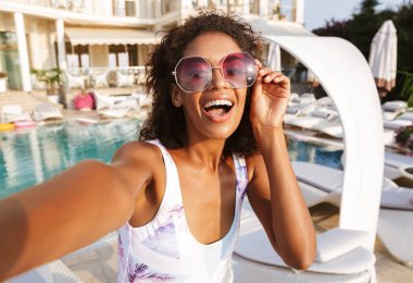 Çekici genç Afrikalı kadın bir selfie iyi vakit ise bir yüzme havuzu tesisi alarak mayo