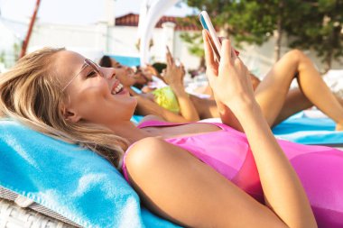 Gülümseyen genç kadın spa merkezi resort adlı dinlenirken cep telefonu tutan mayo giymiş
