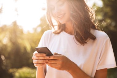 Hareket eden telefon vasıl belgili tanımlık park açık havada kullanan genç kız gülümseyerek
