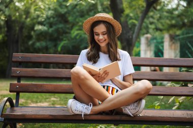 Mutlu genç kız park açık havada otururken bir kitap okuma