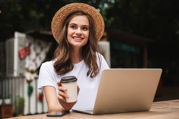 Sonriente Chica Joven Bebiendo Café Mientras Está Sentado Con Ordenador —  Fotos de Stock