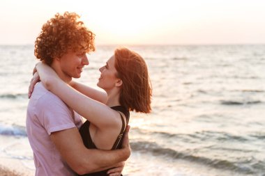 Mutlu bir genç çift sahilde sarılma portresi