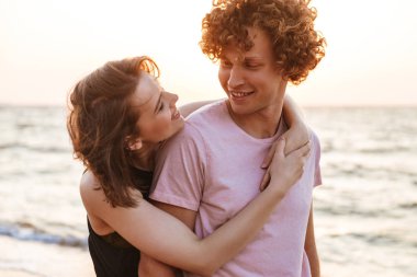 Sevimli genç mutlu sevgi dolu çift açık havada sahilde sarılma görüntü.