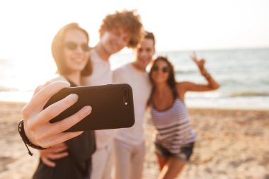 Sevgi dolu mutlu arkadaşlar grup fotoğrafı açık havada beach almak bir selfie tarafından cep telefonu barış hareketi ile çiftler.
