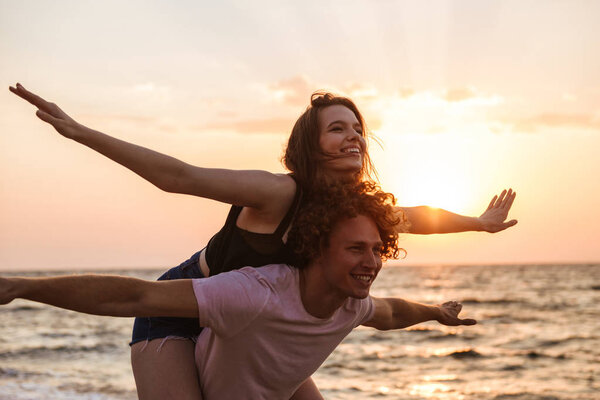 Portrait of a lovely young couple at the beach, having fun, piggyback ride