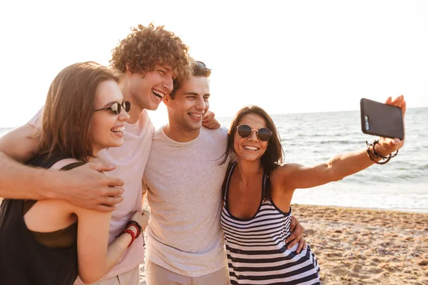 Sevgi dolu mutlu arkadaşlar grup fotoğrafı açık havada beach almak bir selfie cep telefonuyla çiftler..