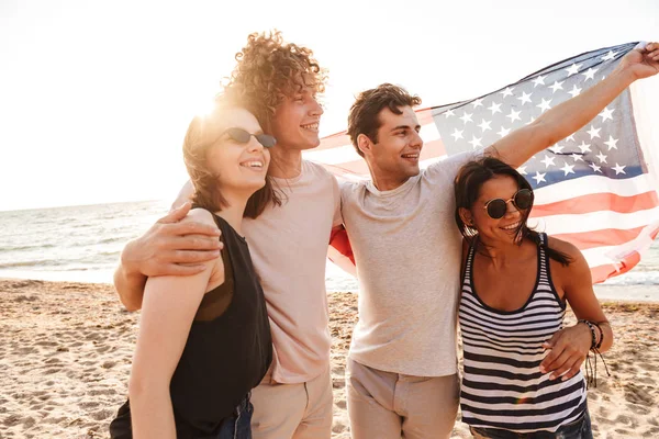 快乐的朋友群的形象在海滩上举行美国国旗有乐趣 — 图库照片