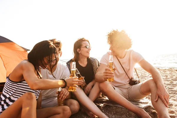 お互いに語り合っているビールを飲みながら座っているビーチの屋外友達の興奮しているグループの写真 — ストック写真