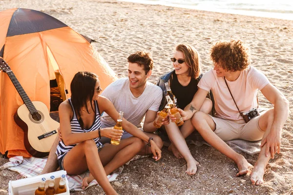 お互いに語り合っているビールを飲みながら座っているビーチの屋外友達の興奮しているグループの写真 — ストック写真