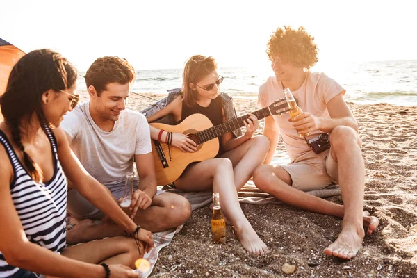 一群积极的年轻朋友一起在沙滩上玩耍 喝啤酒 在露营时弹吉他 — 图库照片
