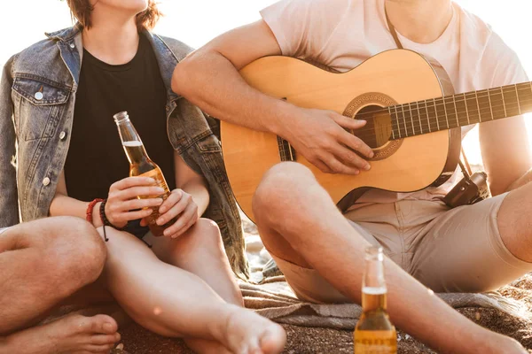 一群欢快的年轻朋友一起在沙滩上玩耍 喝啤酒 在露营时弹吉他的画面 — 图库照片