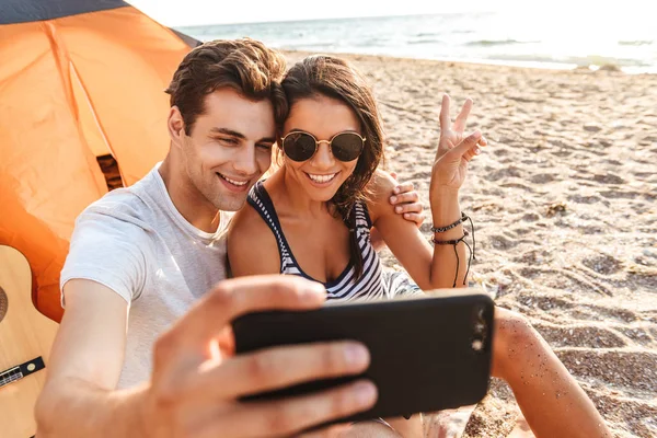 Selfie tarafından cep telefonu açık havada barış hareketi gösterilen sahilde yapmak imge-in genç Sevimli sevgi dolu çift.