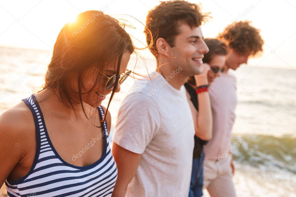 Picture of happy group of friends loving couples walking outdoors on the beach having fun.