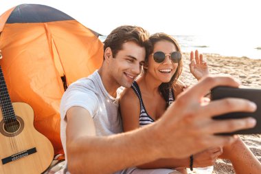 Selfie tarafından cep telefonu açık havada sallayarak sahilde yapmak imge-in genç Sevimli sevgi dolu çift.