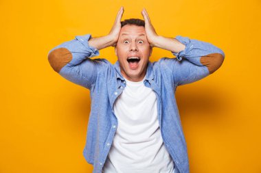 Şok bir orta yaşlı adam başarı sarı arka plan üzerinde izole kutlama portresi