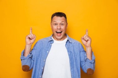 Neşeli bir orta yaşlı adamın parmakları işaret sarı arka plan üzerinde izole portresi
