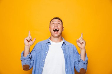 Mutlu bir orta yaşlı adamın parmakları işaret sarı arka plan üzerinde izole portresi