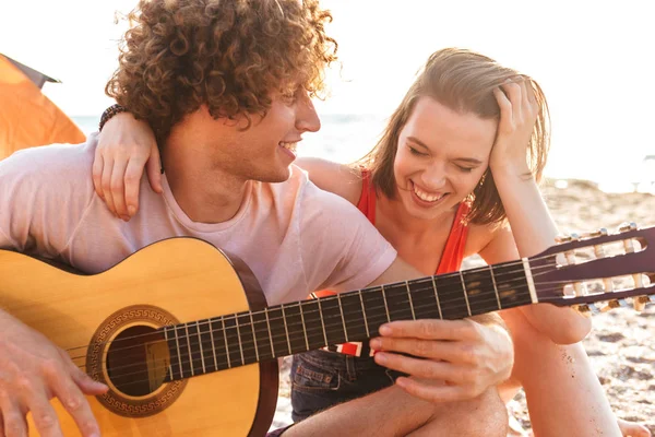 Pareja Joven Positiva Descansando Juntos Playa Acampando Tocando Guitarra —  Fotos de Stock