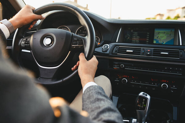 Вид сверху крупным планом бизнесмена в костюме за рулем своей машины
