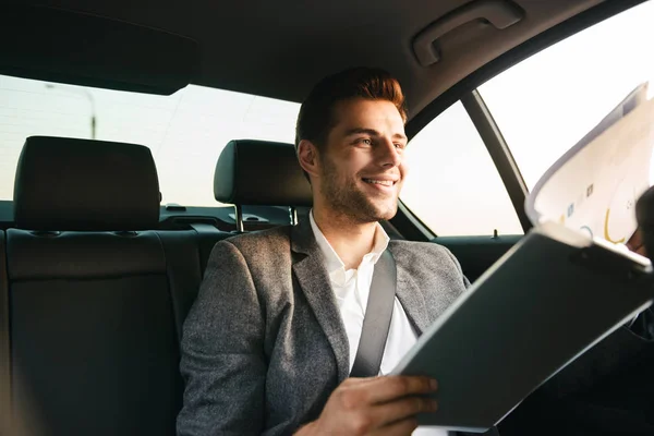 Usmívající Podnikatel Hledá Prostřednictvím Dokumentů Při Sezení Vzadu Auto — Stock fotografie