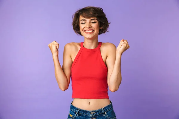 カジュアルな服装の歓喜と 紫色の背景に分離成功で拳を噛みしめながら笑顔でスリムなブルネットの女性の 代の画像クローズ アップ — ストック写真