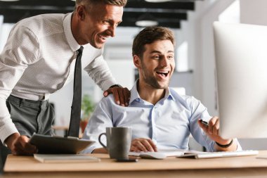 Bilgisayarla çalışma ofisinde heyecanlı mutlu duygusal erkek meslektaşlarının resim.