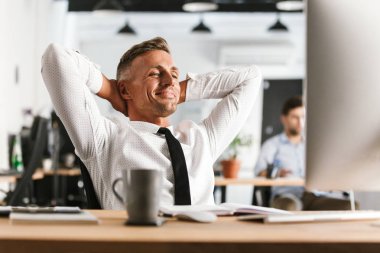 Bilgisayarla çalışma ofisinde oturan yakışıklı mutlu adam resim var bir dinlenme.