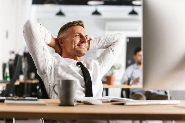 Bilgisayarla çalışma ofisinde oturan yakışıklı mutlu adam resim var bir dinlenme.