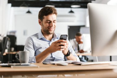 Ofiste tabloda tarafından otururken iş adam yazılı mesaj Smartphone cep telefonu ile gülümseyen