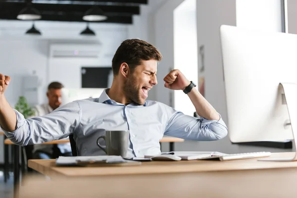 Alegre Gerente Masculino Regocija Mientras Utiliza Ordenador Sentado Junto Mesa —  Fotos de Stock