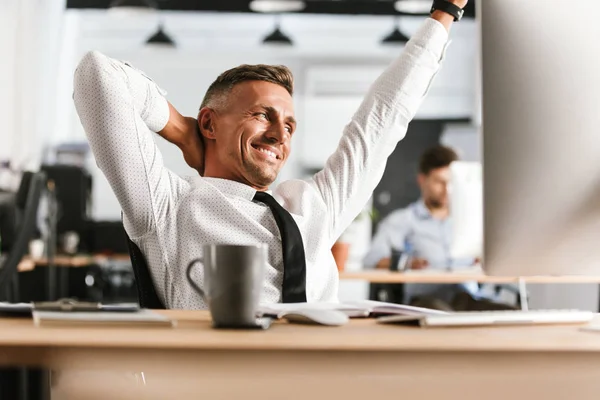 Smilende Middelaldrende Forretningsmann Som Slapper Ser Bort Mens Han Sitter – stockfoto