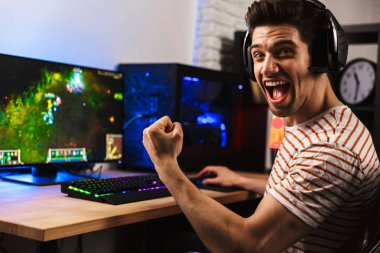 Kulaklıklı, bilgisayar başında video oyunu oynarken bağıran ve sevinen kendinden geçmiş oyuncunun portresi.