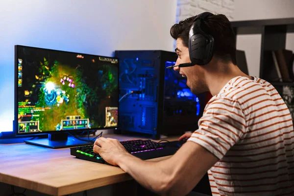 コンピューターでビデオ ゲームをプレイしながら歓喜のヘッドフォンで幸せゲーマー男の肖像 — ストック写真