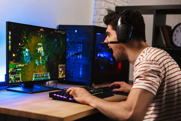 ヘッドセットをコンピューターでビデオ ゲームをプレイしながら叫んで身に着けている怒っているゲーマー男の肖像 — ストック写真