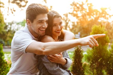 Resim neşeli genç seven açık havada işaret ederken yürüme çift.