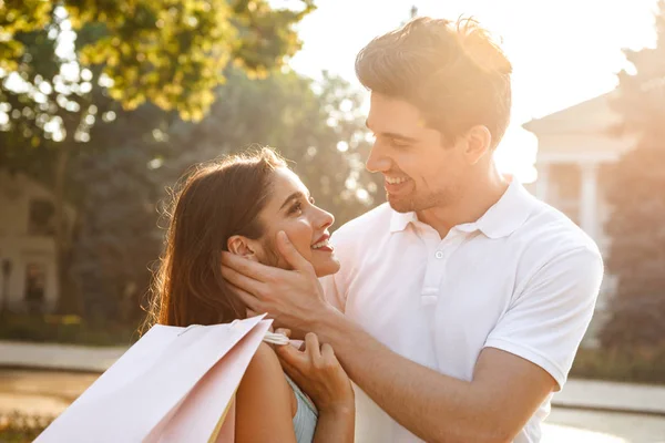 Photo Young Cute Loving Couple Walking Outdoors While Holding Shopping — Stock Photo, Image