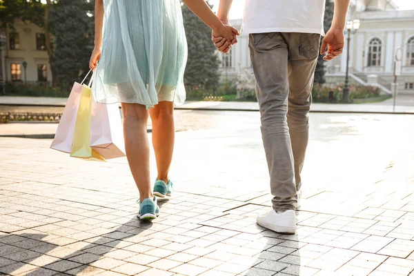 若いかわいい愛するカップル野外を歩いているとショッピング バッグの手をつないで写真をトリミング — ストック写真
