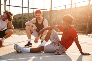 Konuşmak spor yere, dinlenme neşeli çok ırklı gençler basketbol oyuncu grubu