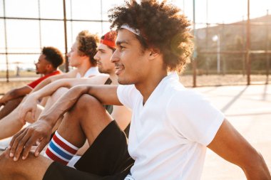 Konuşmak spor yere, oturan genç çok ırklı arkadaşlar basketbol oyuncu grubu
